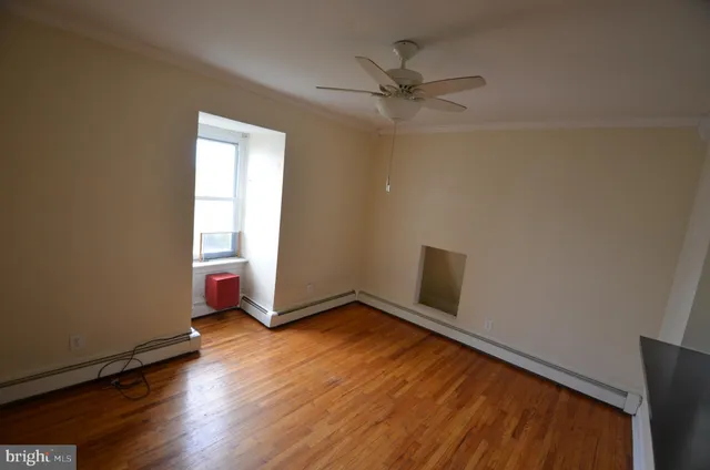 an empty room with wooden floor closet and windows