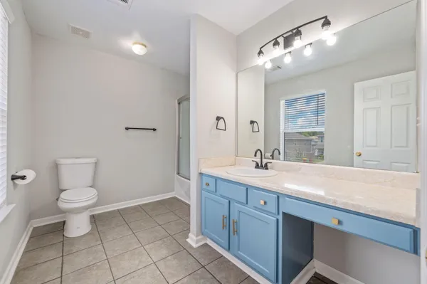 a spacious bathroom with a granite countertop sink a toilet and a mirror