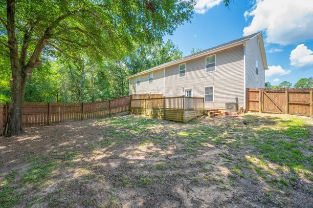 a view of a backyard with a large tree and wooden fence