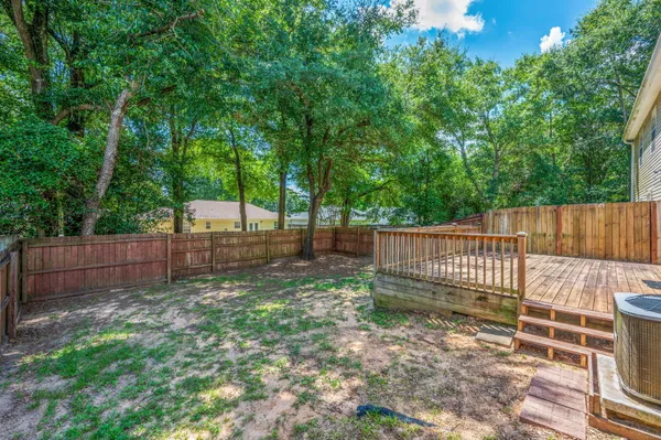 a view of a backyard with large trees and wooden fence