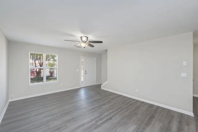 a view of an empty room with wooden floor and window
