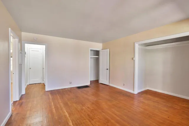 a view of an empty room with window and wooden floor