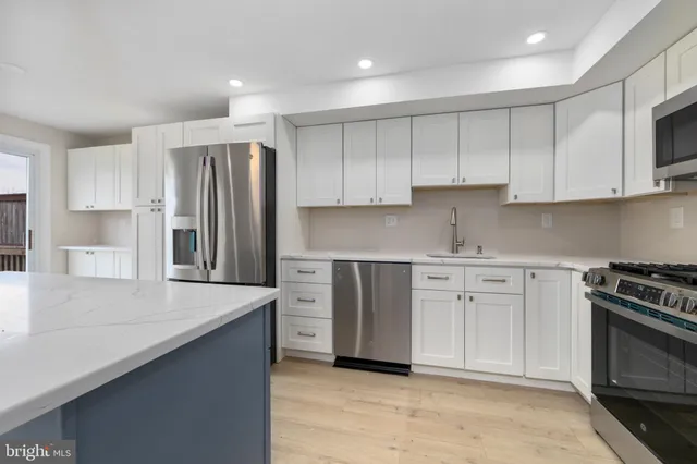 a kitchen with stainless steel appliances granite countertop a refrigerator stove a sink and white cabinets