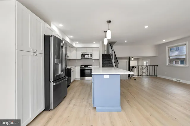 a kitchen with a refrigerator a stove top oven and wooden floor