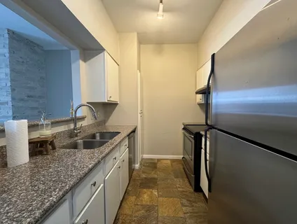 a kitchen with a granite countertop sink and refrigerator