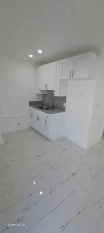a large white kitchen with white cabinets and a sink