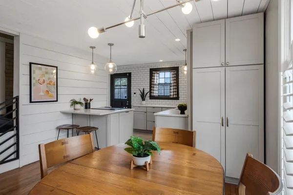 a kitchen with stainless steel appliances granite countertop a refrigerator a sink a stove and a dining table with wooden floor