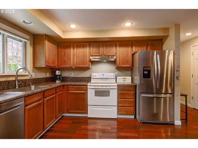 a kitchen with kitchen island granite countertop a refrigerator and a sink