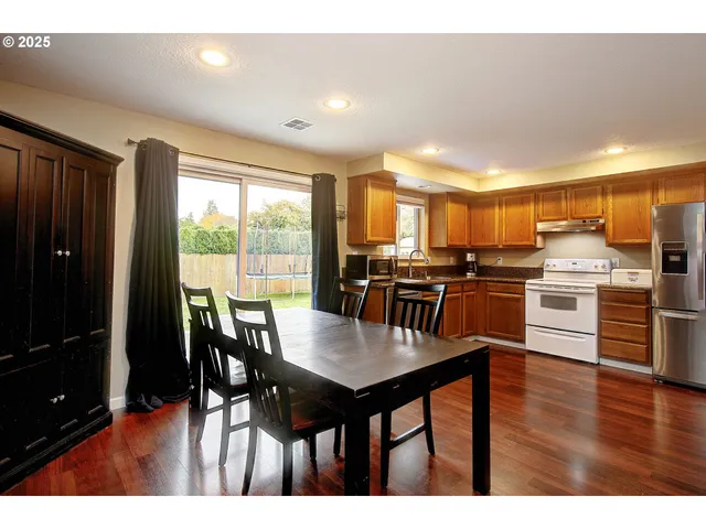 a kitchen with stainless steel appliances wooden floor dining table and chairs