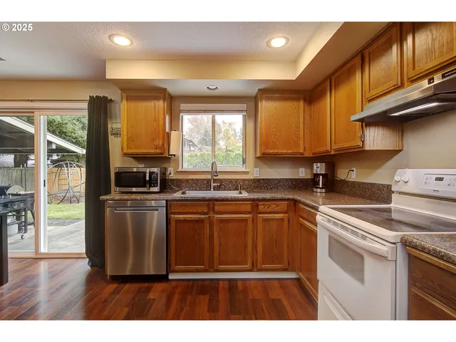 a kitchen with stainless steel appliances granite countertop a stove a sink and a microwave