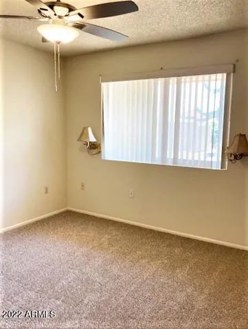 an empty room with a ceiling fan and window