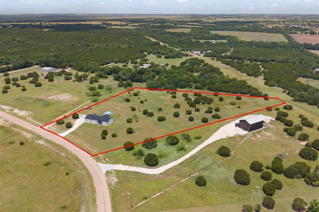 1031 Augustus Court Rio Vista, TX 76093 - Photo 28 of 30 Expansive property featuring two structures, established trees, a curved driveway, and a natural landscape