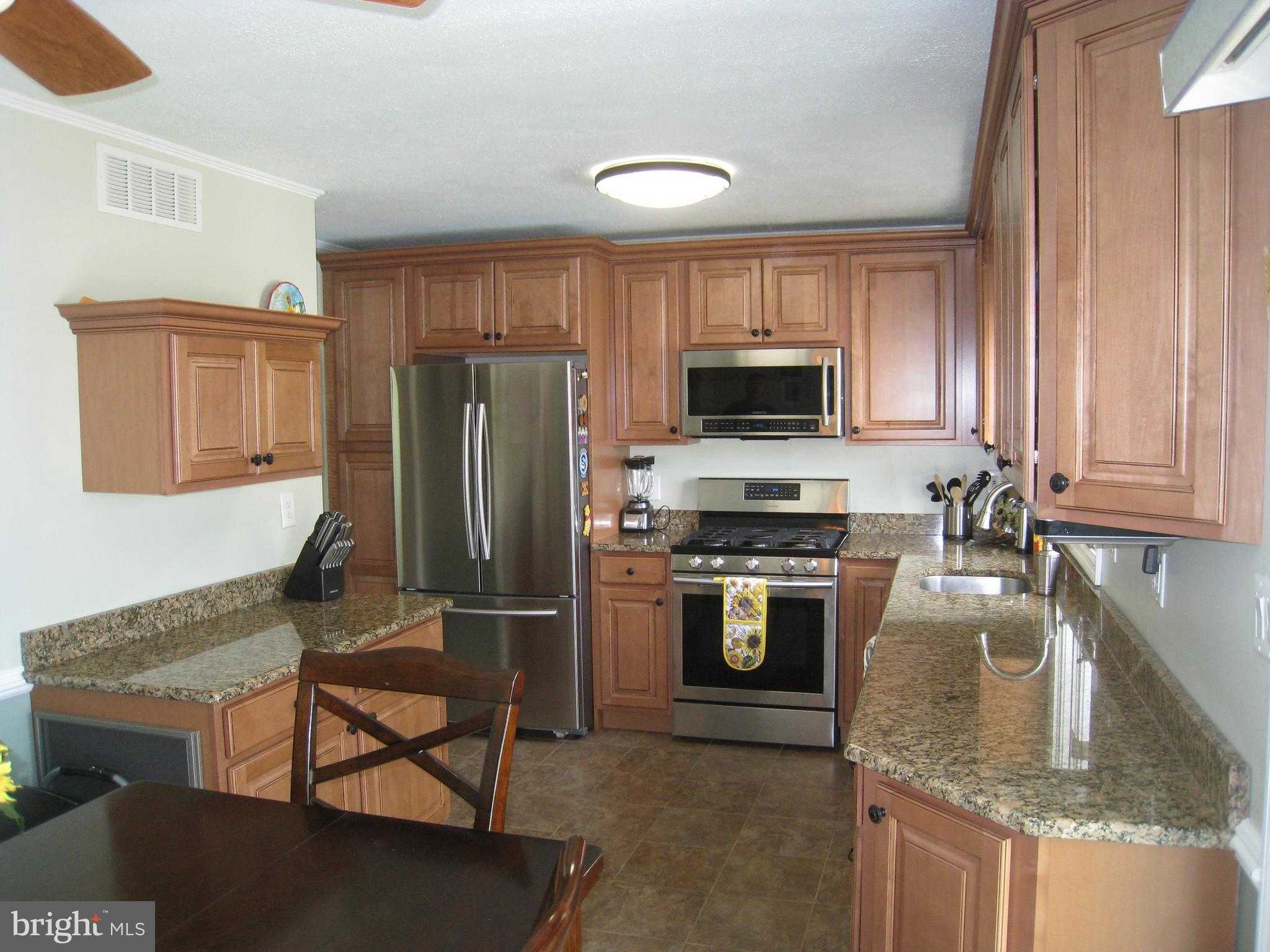 29 Buttonwood Road Stratford, NJ 08084 - Photo 22 of 45 a kitchen with kitchen island granite countertop wooden cabinets stainless steel appliances and a window