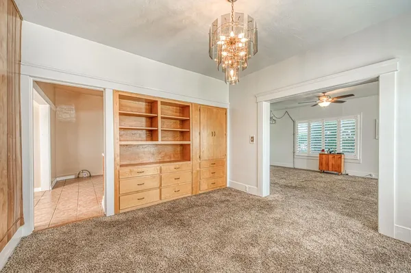 an empty room with chandelier front door and windows