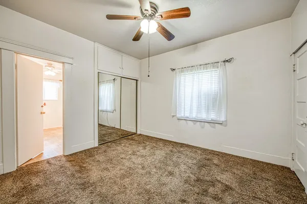 a view of empty room with window and ceiling fan