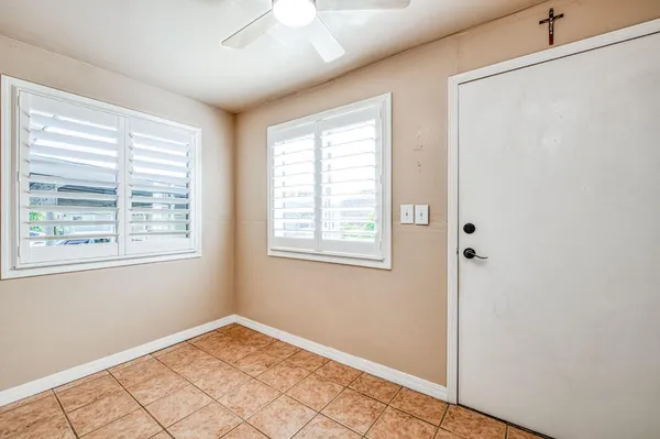 a view of an empty room with window and chandelier fan