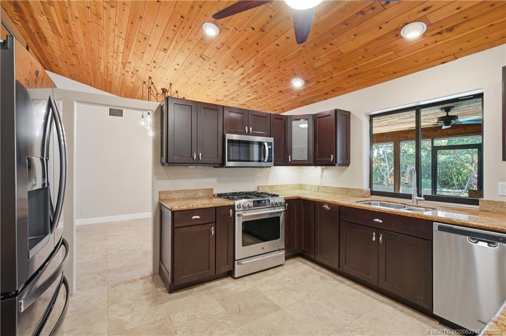 5186 Southeast Harrold Terrace Stuart, FL 34997 - Photo 16 of 50 a kitchen with stainless steel appliances granite countertop a stove sink and refrigerator