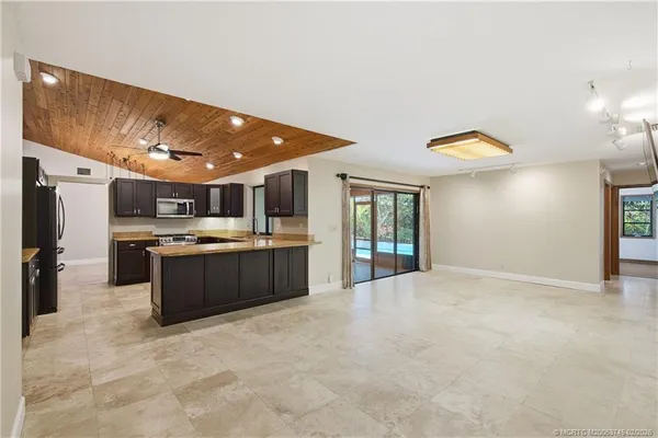 a view of an empty room with kitchen and a sink