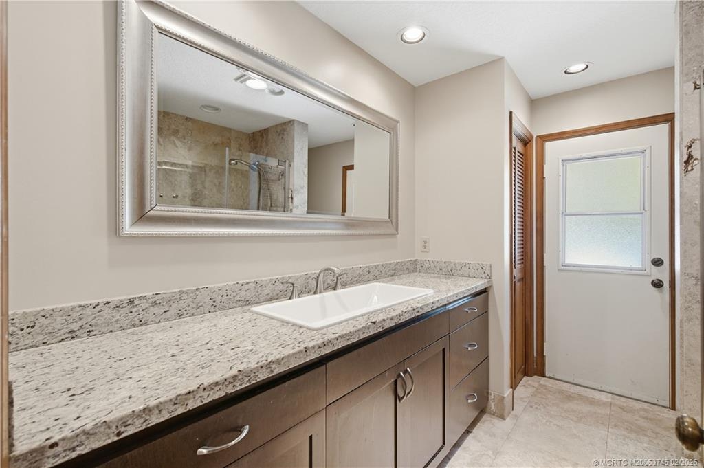 5186 Southeast Harrold Terrace Stuart, FL 34997 - Photo 24 of 50 a bathroom with a granite countertop sink and a mirror