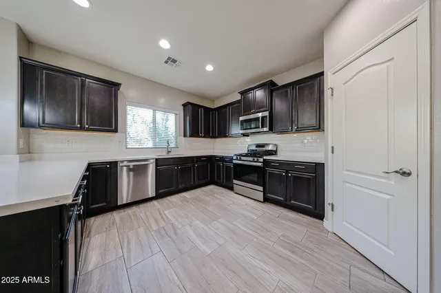 a kitchen with granite countertop wooden floors stainless steel appliances and sink