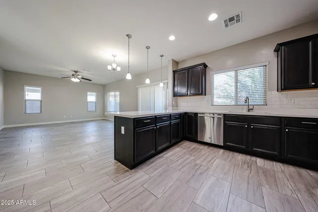a large kitchen with a large counter top a sink stainless steel appliances and cabinets