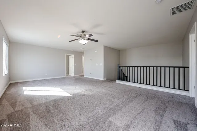 a view of an empty room with a chandelier fan