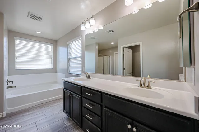 a bathroom with a sink double vanity granite tub and a mirror