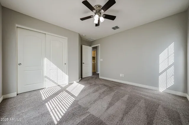 a view of an empty room with window and a ceiling fan