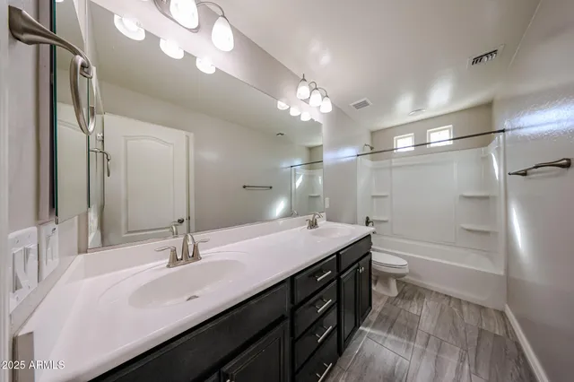 a bathroom with a double vanity sink a toilet and a mirror