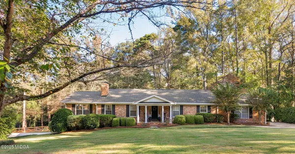 a front view of a house with a garden and trees