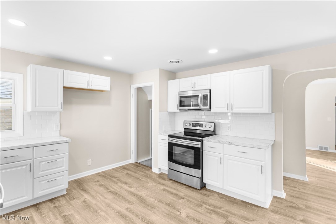 3441 Bell Wick Road Hubbard, OH 44425 - Photo 16 of 22 Kitchen featuring light hardwood / wood-style floors, white cabinetry, backsplash, and appliances with stainless steel finishes