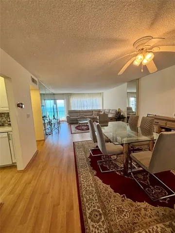 a living room with lots of chairs and a dining table with wooden floor