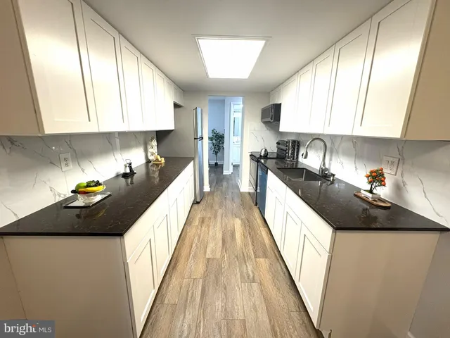 a kitchen with kitchen island granite countertop a sink a counter top space stainless steel appliances and cabinets