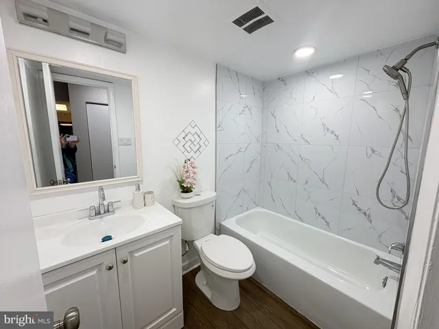 a bathroom with a toilet sink vanity tub and shower