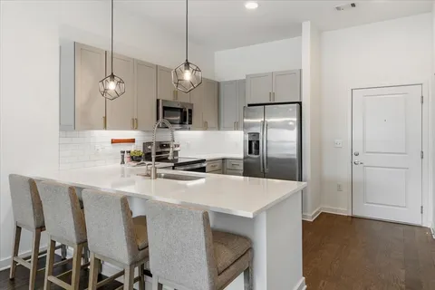 a kitchen with a dining table chairs refrigerator and microwave