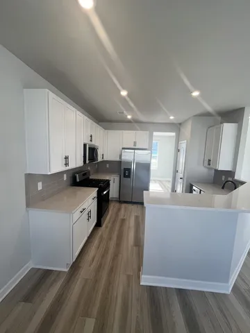 a large kitchen with stainless steel appliances a large counter top a stove and a refrigerator