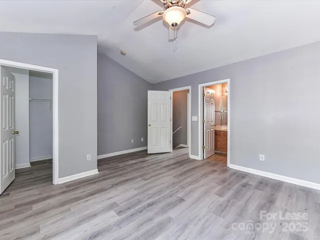 an empty room with wooden floor chandelier fan and windows