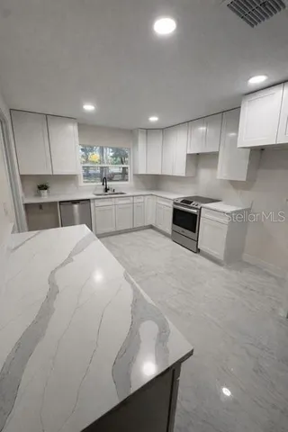 a kitchen with stainless steel appliances a sink a stove a microwave a center island and cabinets