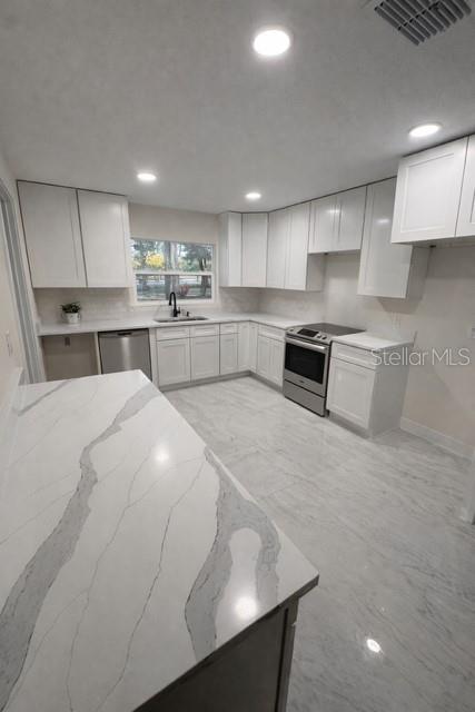 12333 Hancock Road Clermont, FL 34711 - Photo 2 of 3 a kitchen with stainless steel appliances a sink a stove a microwave a center island and cabinets