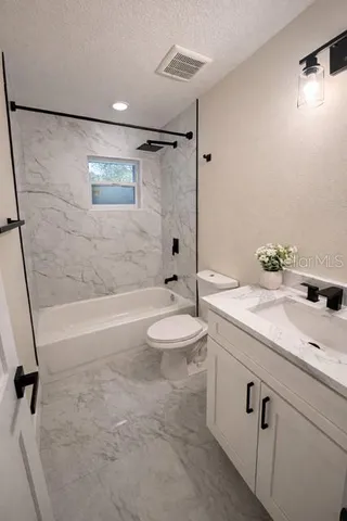 a bathroom with a granite countertop sink toilet a mirror and shower