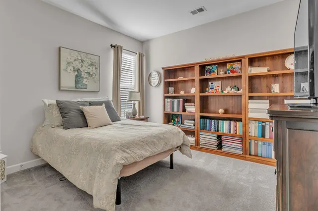 a bedroom with a bed a book shelf and a window
