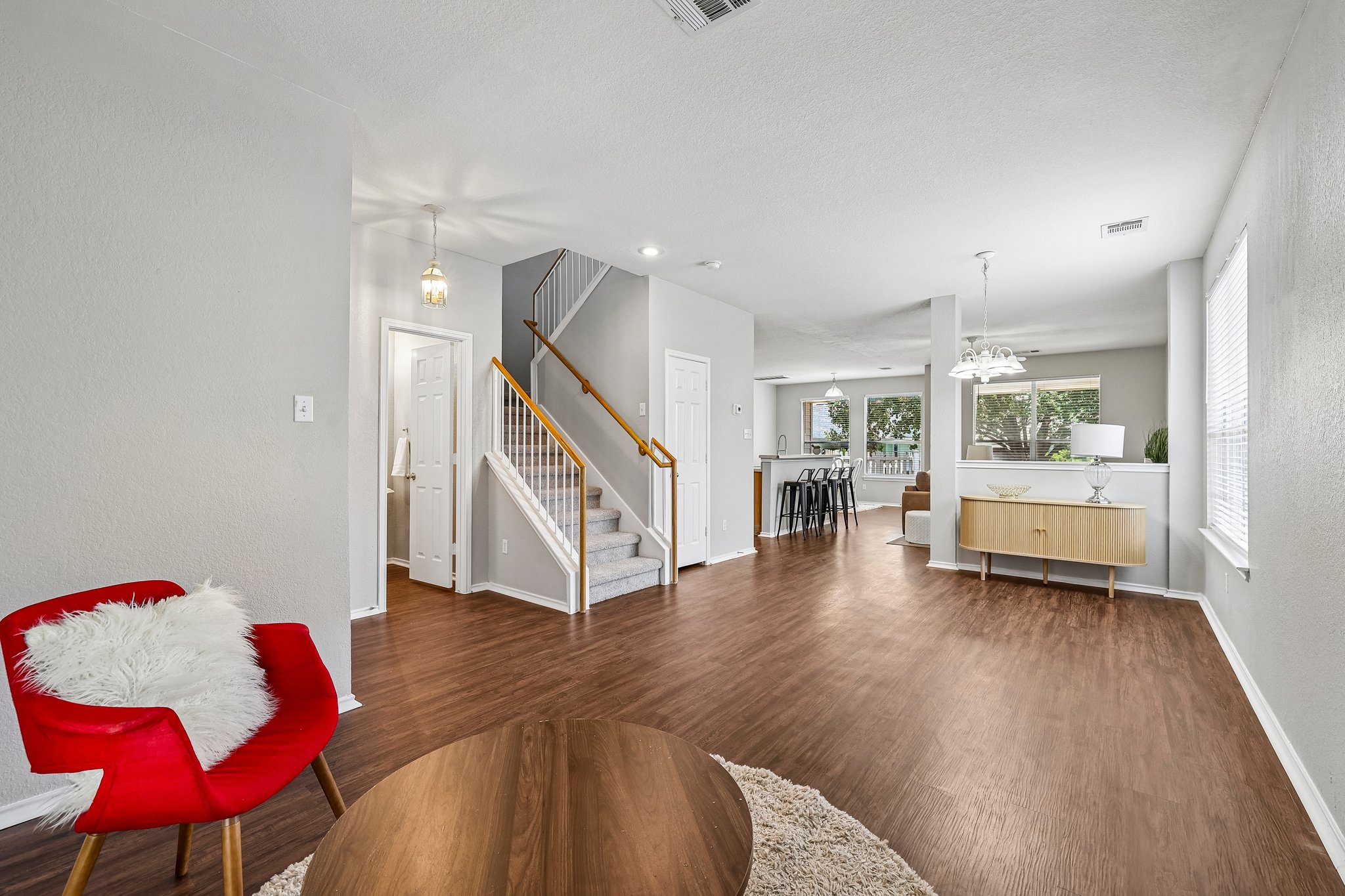 An inviting open-concept living space features warm wood-look flooring and a prominent staircase leading to the upper level.