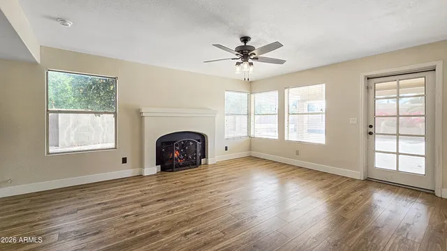 a view of empty room with wooden floor and fan