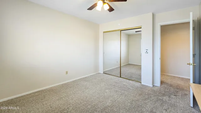 an empty room with a ceiling fan and carpet