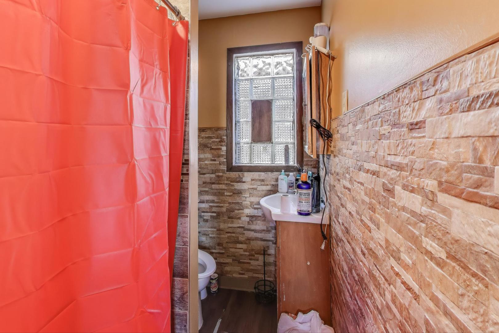 2625 South Central Park Avenue Chicago, IL 60623 - Photo 23 of 36 a bathroom with a shower curtain and a wooden floor
