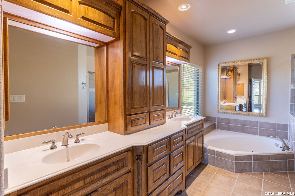 198 Echo Falls Road Comfort, TX 78013 - Photo 16 of 28 a spacious bathroom with a double vanity sink a large mirror a bathtub and next to a window