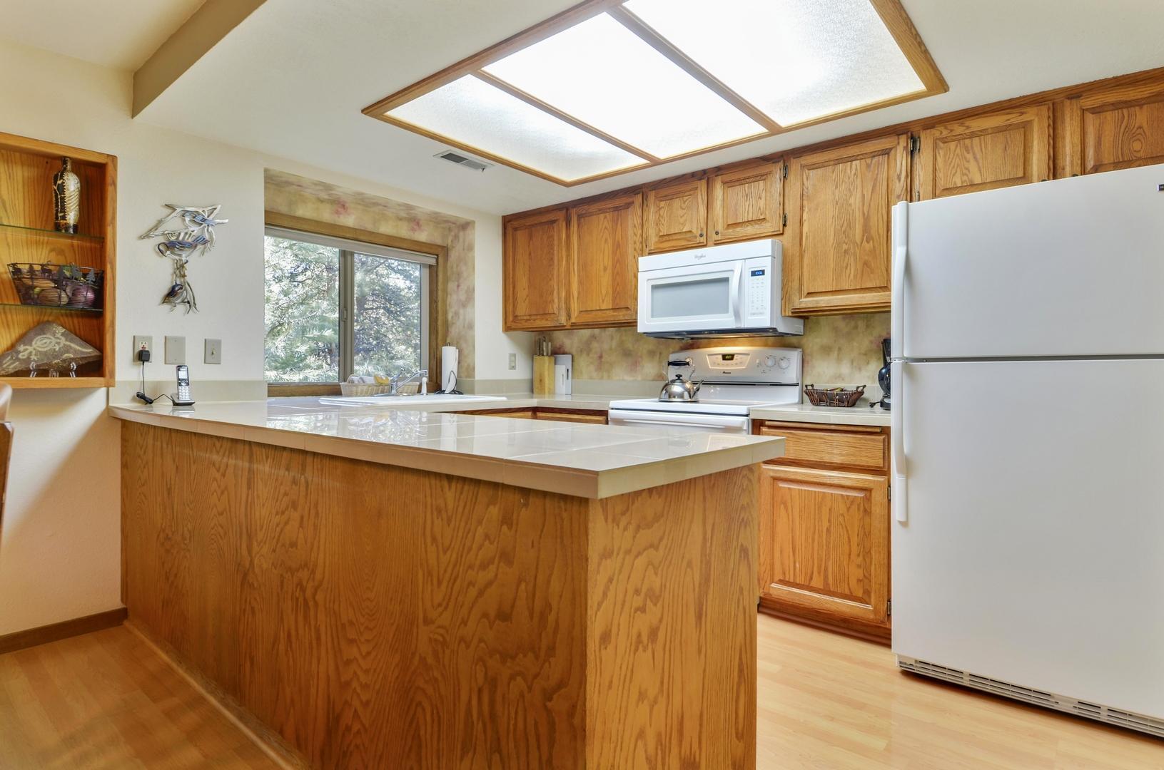 57301 Beaver Ridge Loop, Unit 10 Sunriver, OR 97707 - Photo 8 of 23 a kitchen with stainless steel appliances granite countertop a refrigerator a sink dishwasher a stove with white cabinets and wooden floor