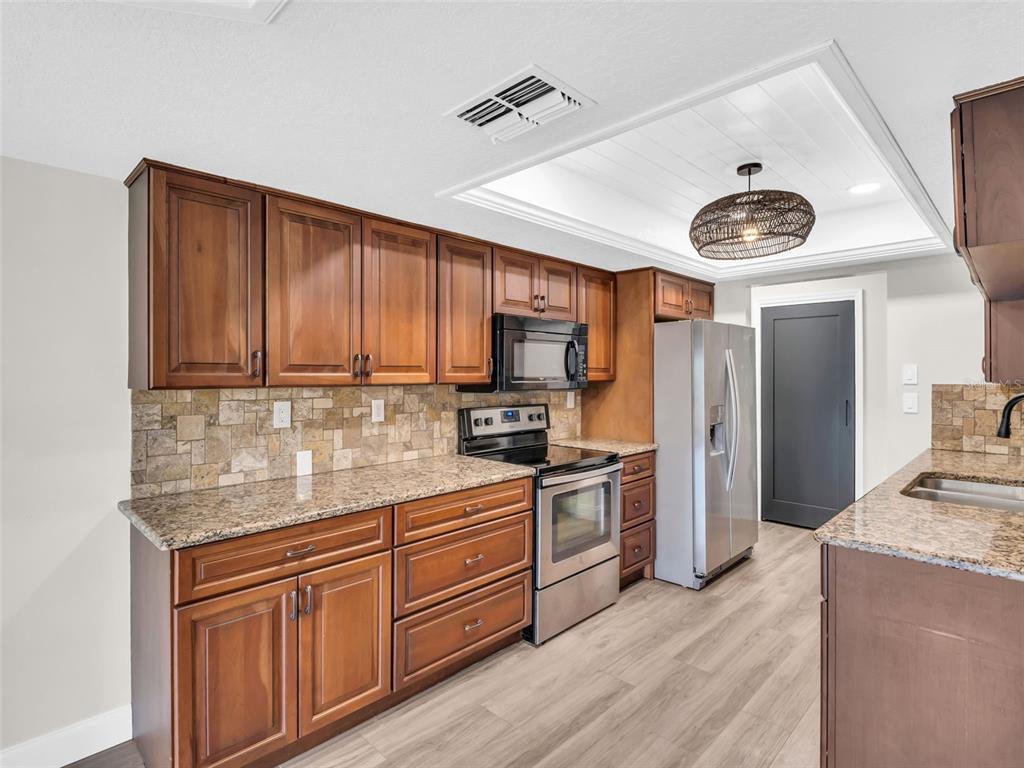 640 Kenneth Way Tarpon Springs, FL 34689 - Photo 11 of 84 a kitchen with stainless steel appliances granite countertop a stove a sink dishwasher and a refrigerator with wooden floor