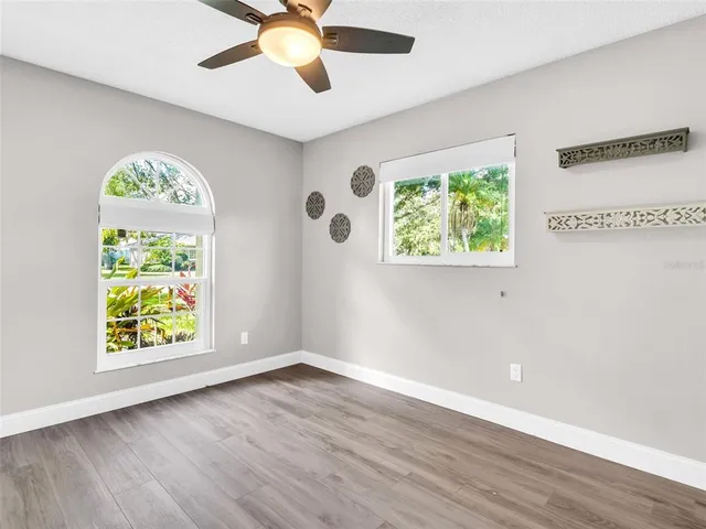 a view of an empty room with a window and wooden floor