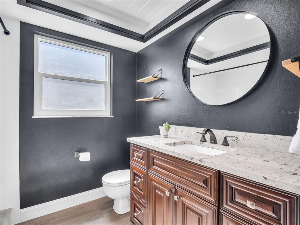 640 Kenneth Way Tarpon Springs, FL 34689 - Photo 33 of 84 a bathroom with a granite countertop toilet a sink and a mirror